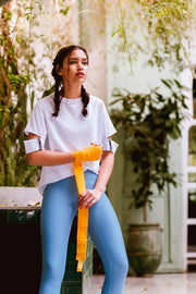 pure by luce sustainable Yattou White sports T-shirt with cut-out sleeves with light blue unicolour Noor Sky leggings worn by a girl with braided hair taping her hands in