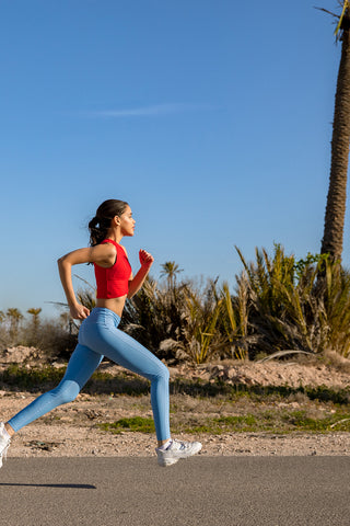 girl running in pure by luce sustainable Gugu Red sports crop top with light blue unicolour Noor Sky leggings with booty controuring