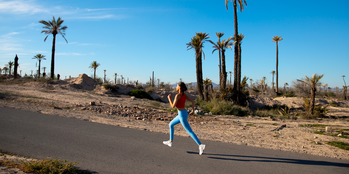 girl running in Morocco with the sun shining wearing pure by luce sustainable light blue unicolour Noor Sky leggings with booty contouring and the Gugu Red sports crop top