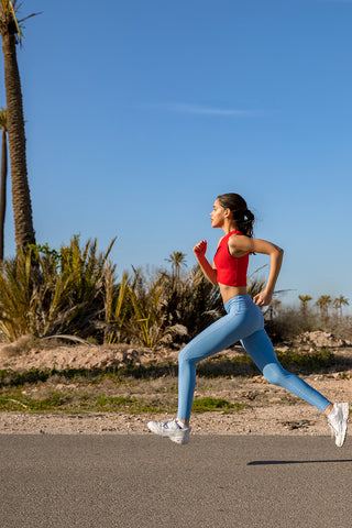 running girl wearing pure by luce sustainable light blue unicolour Noor Sky leggings and the Gugu Red sports crop top