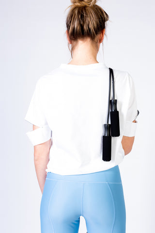 pure by luce sustainable Yattou White sports T-shirt with cut-out sleeves with light blue unicolour Noor Sky leggings worn by a blonde girl carrying a skipping rope over her shoulder