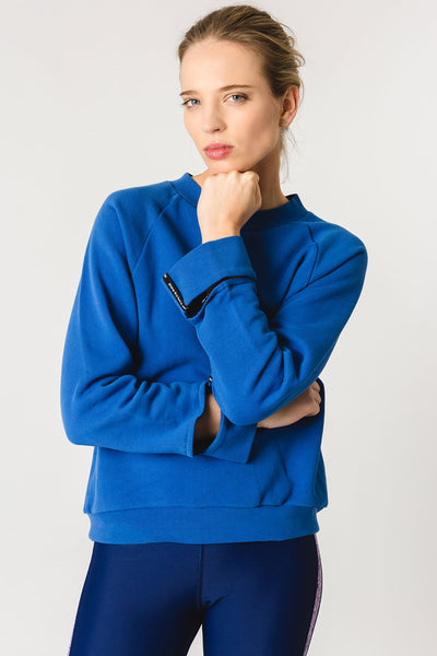 pure by luce sustainable athleisure Nina Blue sweater with cut-out sleeve cuffs and logo detail
