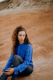 pure by luce sustainable athleisure Nina Blue sweater with cut-out sleeve cuffs and logo detail with dark grey unicolour Noor Petrol leggings with booty contouring