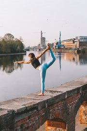 Laura Vantorre in pure by luce sustainable Gugu Black sports crop top with the light blue unicolour Noor Sky leggings with booty contouring in a yoga position